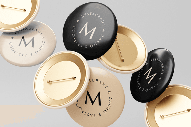 A floating composition of custom cream and black button pins featuring the circular MO FIVE emblem seal.