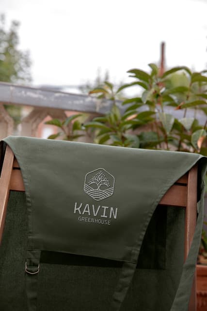 Detailed embroidery of the brand mark on a Forest Green work apron.